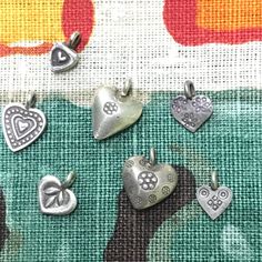 six heart shaped charms sitting on top of a piece of fabric