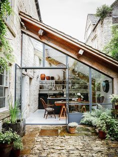 an outdoor kitchen with glass walls and lots of potted plants