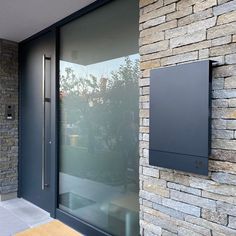 an outside view of a building with a glass door and stone wall behind the entrance