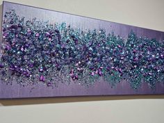 a purple and blue painting with lots of glitter on it's surface, hanging on the wall