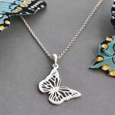 two necklaces one with a butterfly on it and the other with a flower design