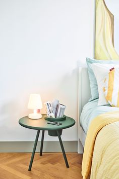 a small table with books on it next to a bed and nightstand in a bedroom