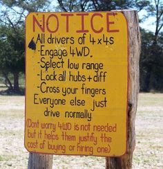 a sign posted on a wooden post in the middle of an open field that says notice all drivers of 4x4s engage