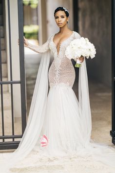 a woman in a wedding dress is holding a bouquet and standing near an open door