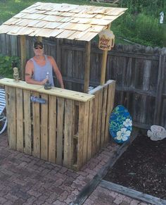 a man sitting at a bar made out of wooden pallets in a backyard area