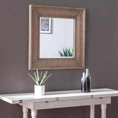 a white table with a mirror above it and two vases on the end tables