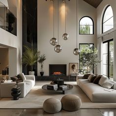 a large living room with high ceilings and lots of windows on the wall, along with modern furniture