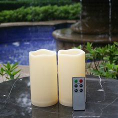 three white candles sitting next to each other with a remote control on top of them