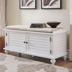 a white bench with two pictures on the wall and a bowl sitting on top of it