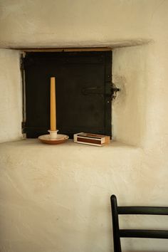 a candle and some books on a window sill in a room with white walls