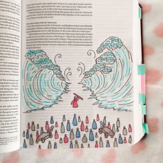 an open book with drawings on it and water in the middle, sitting on a bed