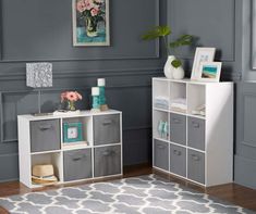 a living room with gray walls and white shelves filled with storage bins on top of each shelf