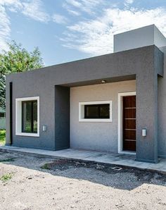 a small gray house sitting on top of a dirt field