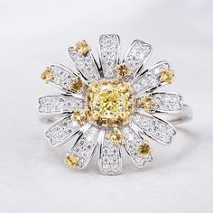 a fancy ring with yellow and white diamonds on the center, surrounded by smaller round brilliant stones