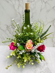 a vase filled with flowers and greenery next to a bottle