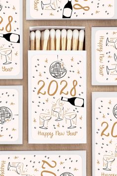 new year's cards and matchesticks are arranged on a table with gold foil lettering