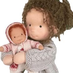 a small doll holding a baby doll in it's arms and wearing a sweater