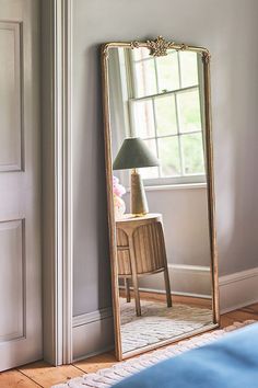 a large mirror sitting on top of a wooden floor next to a bed in a room