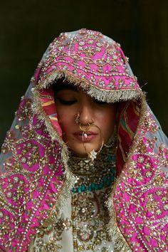 a woman wearing a pink and gold veil with her nose ring in the shape of a heart