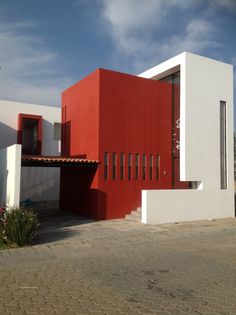 a red and white house on the side of a road in front of a blue sky