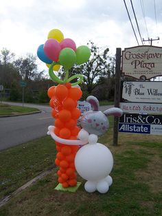 an inflatable bunny and rabbit balloon stand next to a street sign