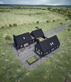 an aerial view of two black houses in the middle of a field