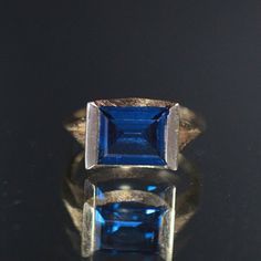 Absolutely Beautiful! Featuring This 14k Gold Ring Mounted With 3.29 Cts Squared Blue Synthetic Spinel Bezeled Set In A Textured Modernist Setting. This Is Size 6 And Weighs 3.38 Grams. Stock Code: 2p2205-3-24 Blue Rectangular Diamond Cut Jewelry, Blue Emerald Cut 14k Gold Sapphire Ring, Timeless Blue Jewelry With Prong Setting, Modern Blue Sapphire Ring In 14k Gold, Modern Blue Sapphire Ring For Formal Occasions, Modern Blue Diamond Cut Jewelry, Timeless Blue Topaz Ring Gift, Elegant Blue Sapphire Ring In 14k Gold, Vintage Blue Topaz Ring With Diamond Cut