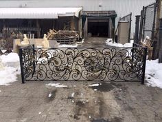 a wrought iron gate in front of a building with snow on the ground around it