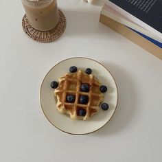 a white plate topped with blueberries and waffles next to a cup of coffee