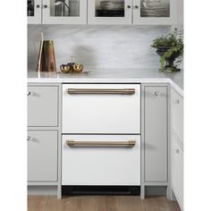 a kitchen with white cabinets and gold handles