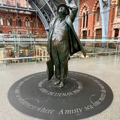 a statue in the middle of a building with writing on it and a man holding a hat