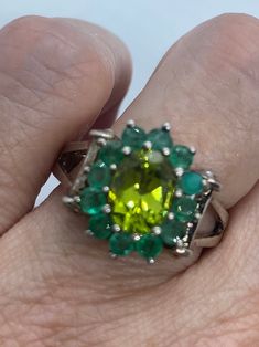 Rich and very bright green peridot ring surrounded by Emerald  Sterling silver  Size 8 can be sized by my jeweler. His service charge is $20  All rings are shipped in a nice gift box.   Check out our over a THOUSAND great reviews Engraving is $4 per letter and is not always perfect depending on the piece. It can take a few days if the jeweler is busy. This is payable to Paypal Judithsltd@gmail.com  PLEASE NOTE If we have multiples of the same vintage item, it is because we often purchase factory Green Emerald Ring With Accent Stones For May Birthstone, Emerald Cut Green Gemstones With Accent Stones, Green Emerald Ring Gift, Green Emerald Ring For Gift, Fine Jewelry In Green Peridot, Green Emerald Ring With Center Stone As Gift, Fine Jewelry Lime Green Gemstone, Fine Jewelry Green Rings For May Birthstone, Green Emerald Cut Gemstones For Anniversary