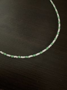 a green and white beaded necklace sitting on top of a table