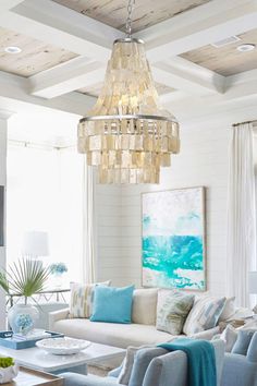 a living room filled with furniture and a chandelier hanging over the top of it