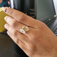 a woman's hand with a ring on her finger next to a coffee cup