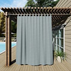 a white curtain hanging on the side of a wooden deck next to a swimming pool