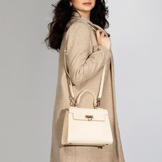 Layla Cream Top Handle & Crossbody Bag: Introducing Levantine 's newest addition: the cream top handle bag. Designed for the modern woman, this bag combines classic charm with contemporary flair. Its sleek silhouette and neutral shade make it a versatile accessory for any occasion. Whether you're running errands or attending a formal event, this bag is the perfect companion. Crafted with meticulous attention to detail, it exudes luxury and refinement. Elevate your look with Levantine's cream top handle bag. Bag Specifications Material: Vegan leather Interior: Luxurious suede lining Handles: Single handle, Removable shoulder strap Hardware: Golden-tone metal flap Pockets: One inner zipped pocket Closure: Front flap closure Size and Fit- Height: 20 cms / 7.9 In Handle Height: 10 cm / 3.9 In Timeless Beige Shoulder Bag With Handle Drop, Luxury Neutral Satchel Shoulder Bag, Luxury Neutral Top Handle Shoulder Bag, Luxury Bag With Detachable Strap In Neutral Color, Luxury Bags With Detachable Strap In Neutral Color, Elegant Satchel With Round Handle For Work, Elegant Workwear Satchel With Round Handle, Luxury Neutral Bags For Formal Occasions, Timeless Beige Double Handle Satchel