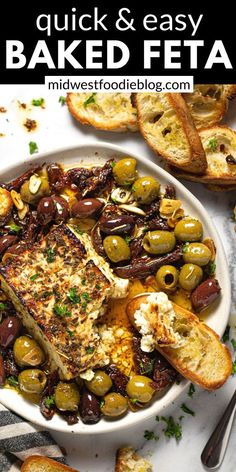 baked feta with olives in a white bowl on a marble counter top next to bread