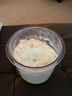 a plastic cup filled with whipped cream sitting on top of a black table next to a white napkin