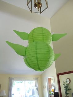 a green paper lantern in the shape of a turtle hanging from the ceiling above a bed