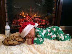 a baby laying on top of a bed next to cookies