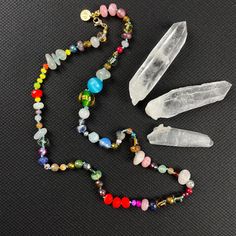 Dive into a kaleidoscope of color with our handcrafted Crystal Confetti Bead Necklace, a statement piece that promises to be as unique as you are. Each bead is lovingly hand-knotted, creating a flow of hues and textures that dance along a durable, colorful nylon cord. 🌟 Highlights:     Hand-knotted for durability and unique design     A vibrant mix of gemstones, glass, wood, ceramic, and resin beads     Bead sizes vary from 2-14mm for a dynamic visual texture     Approximately 21.5 inches in length, perfect for layering or as a standalone statement     Finished with lustrous gold plated stainless steel findings     Receive the exact necklace pictured in the photos 📏 Length: This enchanting necklace measures approximately 21.5 inches, a versatile length that complements both high and low Bohemian Rainbow Crystal Necklaces With Faceted Beads, Bohemian Rainbow Crystal Necklace With Faceted Beads, Bohemian Rainbow Crystal Necklaces With Colorful Beads, Bohemian Rainbow Crystal Necklace With Colorful Beads, Adjustable Rainbow Crystal Bohemian Necklace, Adjustable Rainbow Crystal Bohemian Necklaces, Bohemian Rainbow Faceted Beads Jewelry, Adjustable Rainbow Crystal Necklace With Faceted Beads, Adjustable Rainbow Bohemian Crystal Necklace