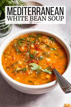 a bowl of mediterranean white bean soup on a table with bread and herbs in the background