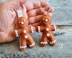 two small gingerbread man keychains are being held by a person's hand