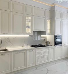 a kitchen with white cabinets and marble counter tops