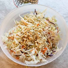 a bowl filled with coleslaw and carrots on top of a table