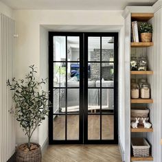 an entry way with glass doors and shelves on either side of the door is a potted plant