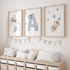 three framed pictures hang on the wall above a bench with pillows and pillow cases in front of it