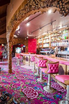 the inside of a restaurant with pink chairs and colorful carpeting on the floor,