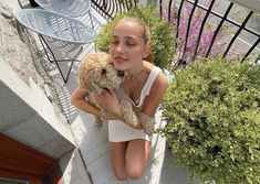 a girl is holding a dog on the porch